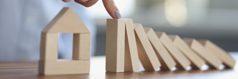 Persons,Hand,Stops,Wooden,Dominoes,From,Falling,On,Wooden,House