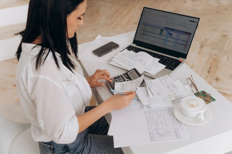 Side,View,Of,Confident,Woman,Calculates,Utility,Expenses,On,Laptop