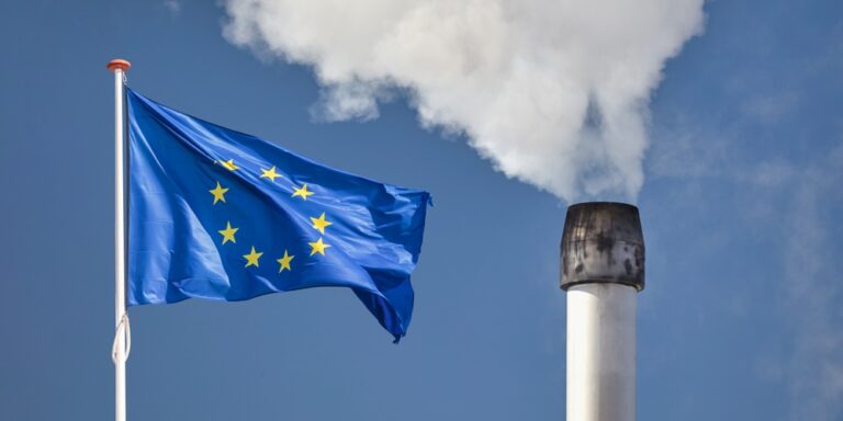 Waving,European,Flag,In,Front,Of,A,Polluting,Factory,Chimney