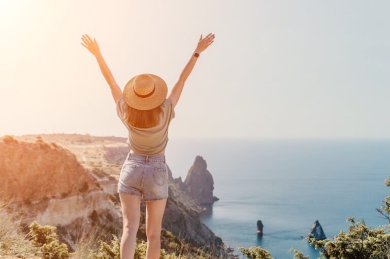 Woman,In,Hat,Raises,Her,Arms,Over,Ocean,View