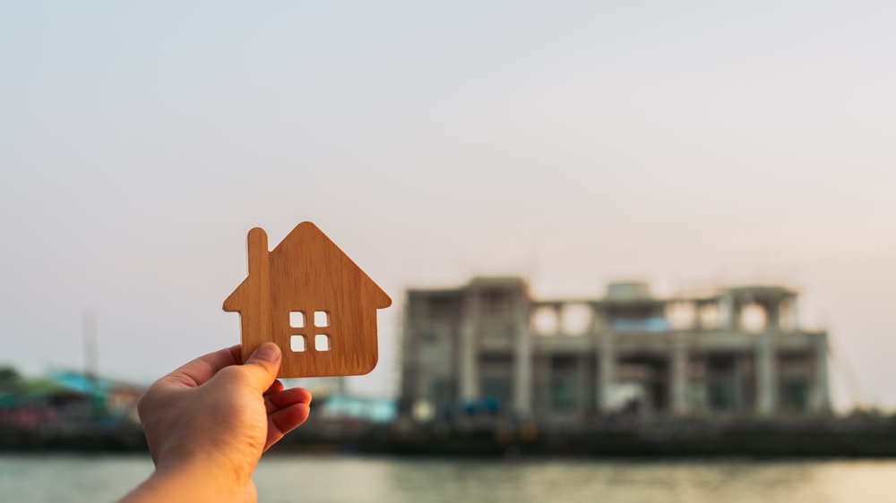 Investors,Hold,Up,A,Model,Of,A,Wooden,House,At