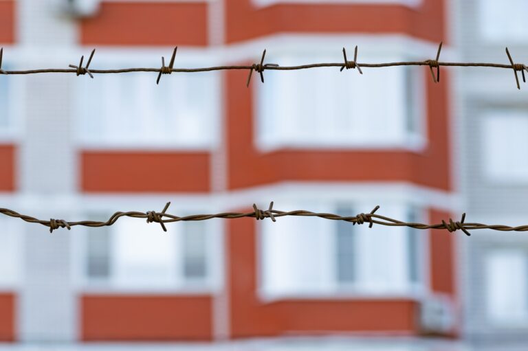 Barbed,Wire,Against,The,Background,Of,A,Residential,Building.,Concept
