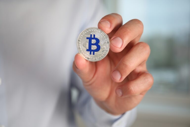 Cryptocurrency.,Man,With,Silver,Bitcoin,On,Blurred,Background,,Closeup.,Space