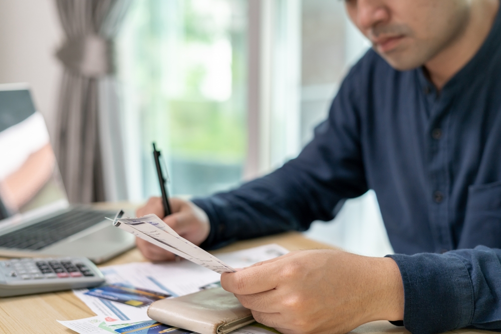 Stressed,And,Headache,Asian,Man,With,Large,Bills,Or,Invoices