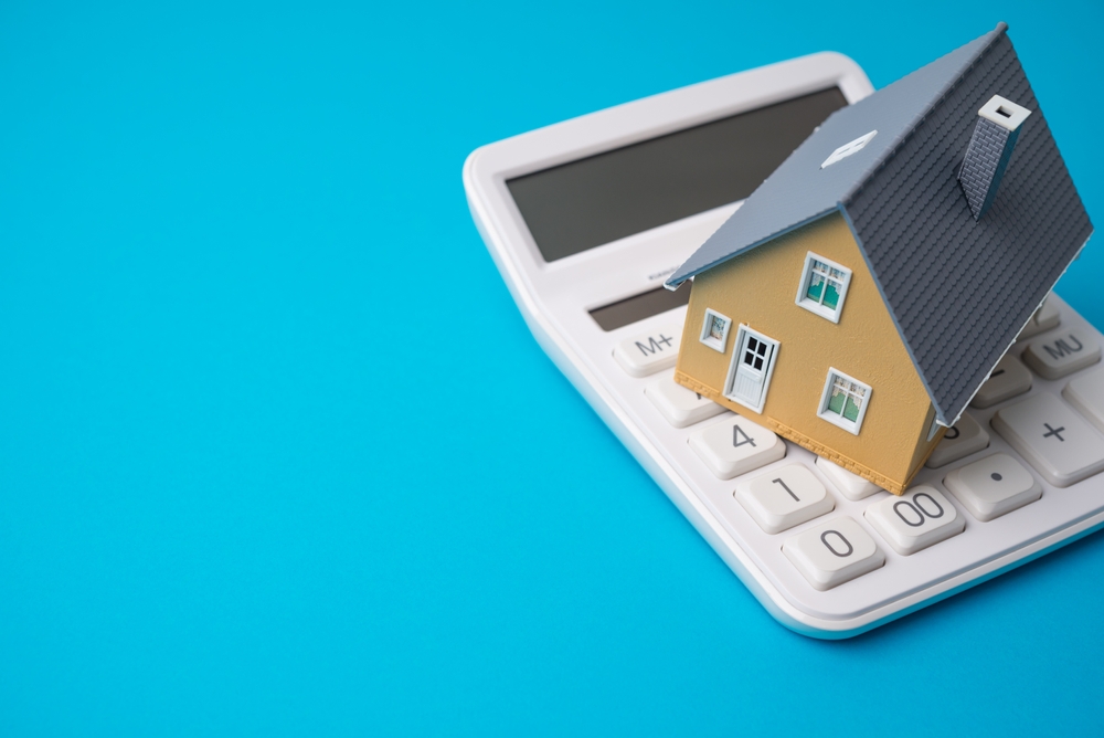 House,Model,On,White,Calculator,With,Blue,Background,Copy,Space.