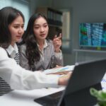 Two,Young,Businesswomen,Discuss,The,Details,Of,Their,Planning,,Operations,