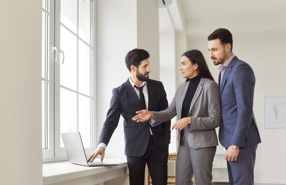 Portrait,Of,Confident,Man,Professional,Realtor,Standing,With,Couple,Clients