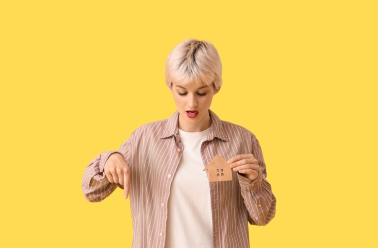 Portrait,Of,Beautiful,Young,Woman,With,House,Model,Pointing,Down