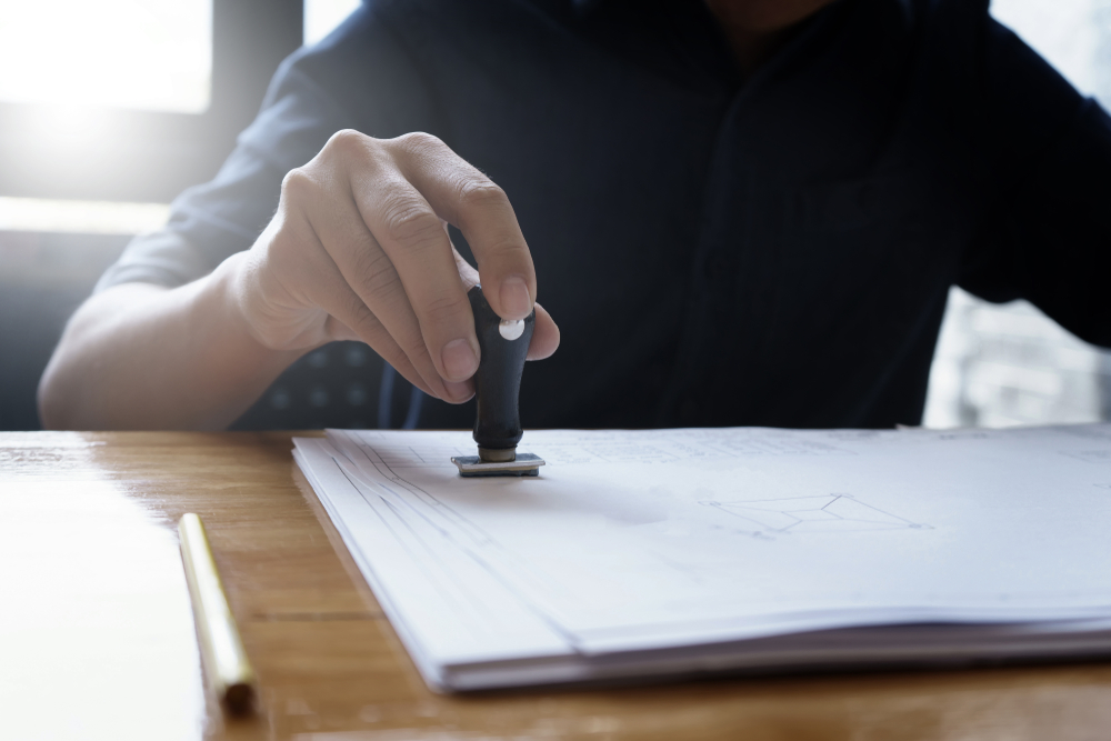 Architect,Or,Engineer,Stamping,The,Document,Or,Blueprint,On,Wooden