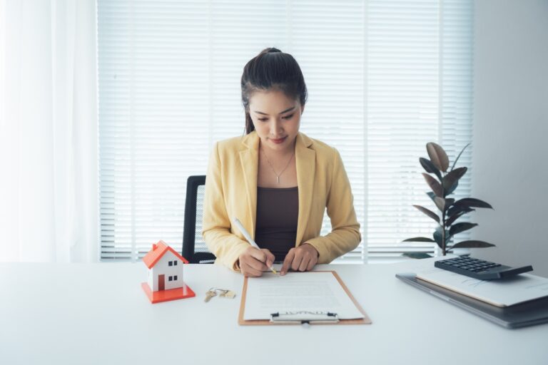 Woman,Signing,Real,Estate,Contract,At,Desk
