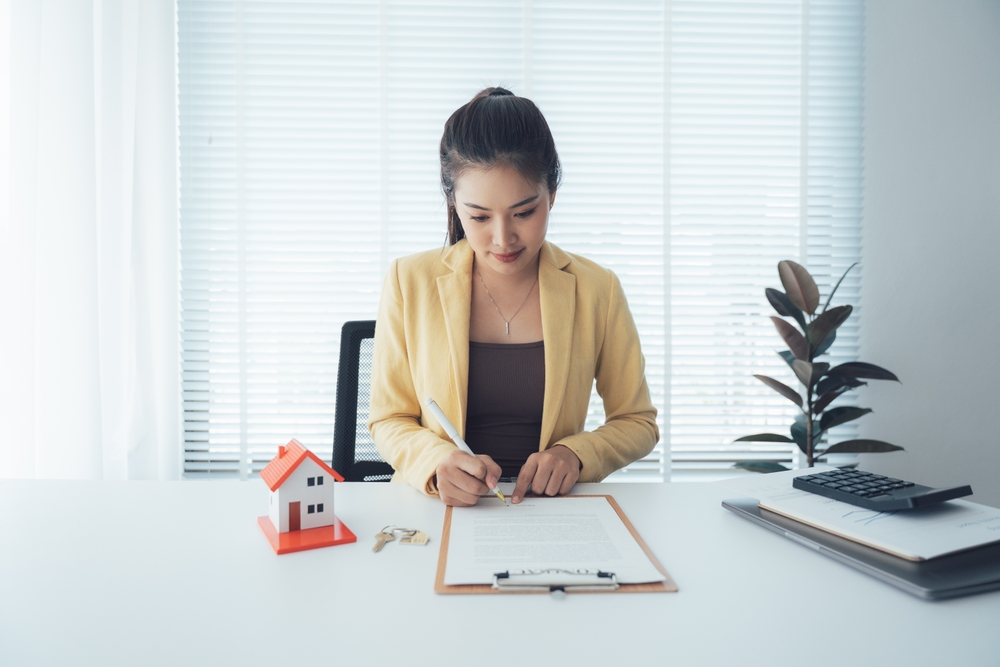 Woman,Signing,Real,Estate,Contract,At,Desk