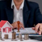 Businessman,Calculating,Real,Estate,Investment,,With,House,Model,,Coins,,And