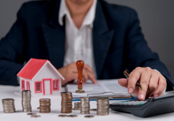 Businessman,Calculating,Real,Estate,Investment,,With,House,Model,,Coins,,And