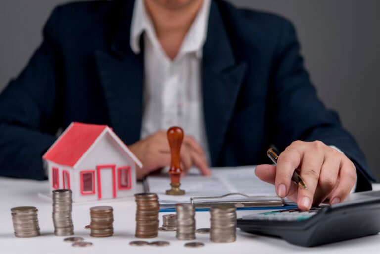 Businessman,Calculating,Real,Estate,Investment,,With,House,Model,,Coins,,And
