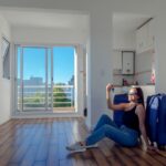 Happy,Woman,Sitting,On,The,Floor,With,Her,Blue,Suitcases