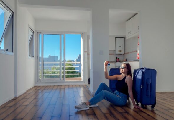 Happy,Woman,Sitting,On,The,Floor,With,Her,Blue,Suitcases