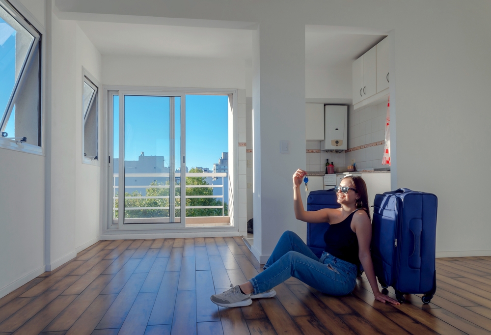 Happy,Woman,Sitting,On,The,Floor,With,Her,Blue,Suitcases