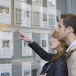 Side,View,Of,A,Young,Couple,Looking,At,Window,Display