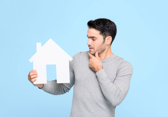 Young,Man,Looking,At,House,Model,And,Thinking,Isolated,On
