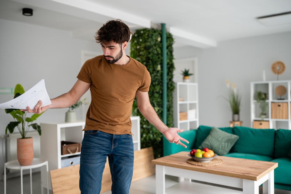 Confused,Man,Holding,Paper,Instructions,While,Trying,To,Assemble,Flat-pack