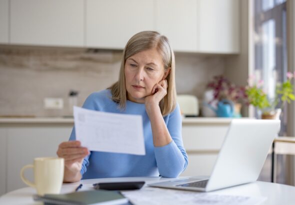 Mature,Woman,Analyzing,Financial,Documents,And,Bills,,Calculating,Expenses,,And