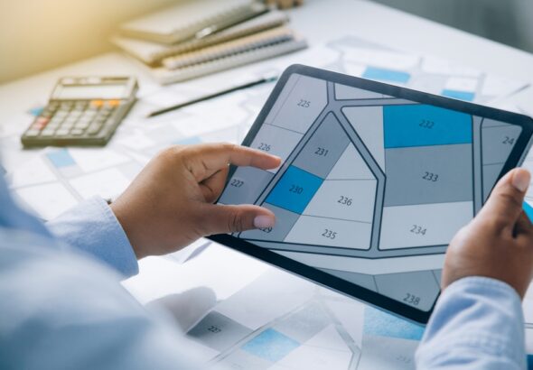 Man,Holding,A,Tablet,Looking,At,Lots,Of,Lands.,Land