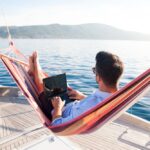 Working,In,Sea,Traveling.,Man,With,Laptop,In,Beach,Hammock.