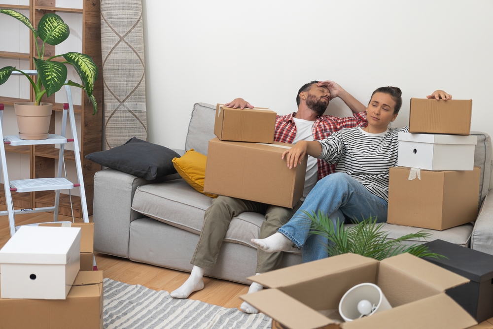 Tired,Man,And,Woman,Relaxing,On,Sofa,After,Carrying,Packed