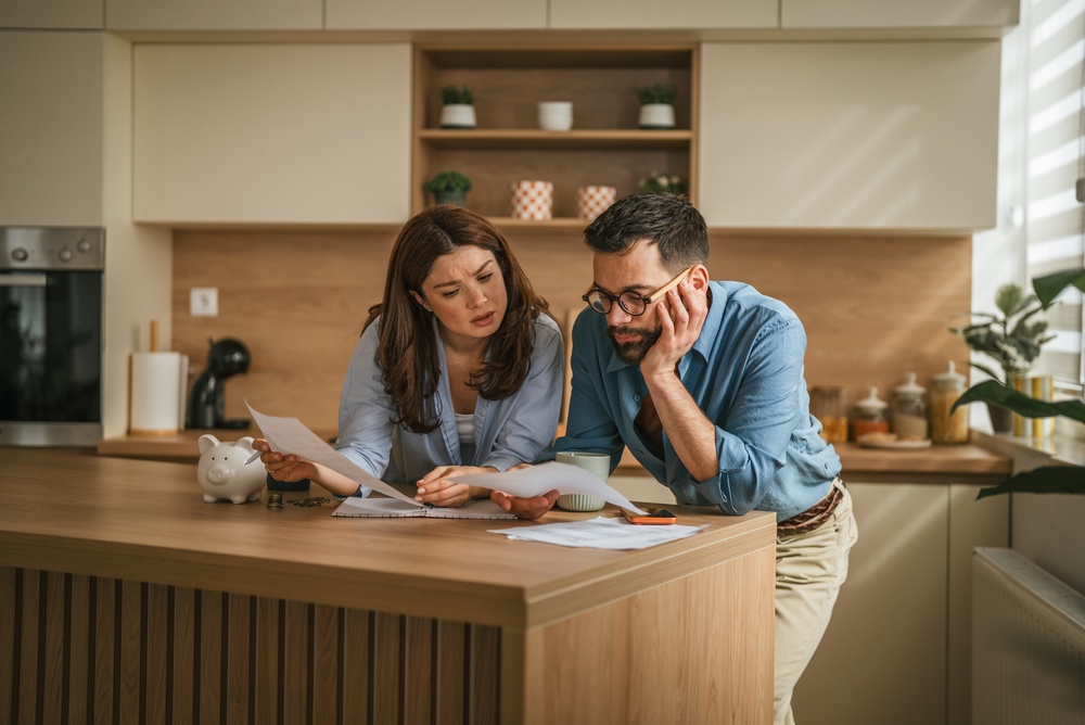 Young,Couple,In,Their,Kitchen,Reviewing,Important,Bills,And,Documents,