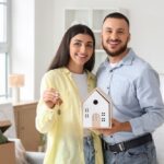 Happy,Young,Couple,With,House,Figure,And,Key,To,Rented