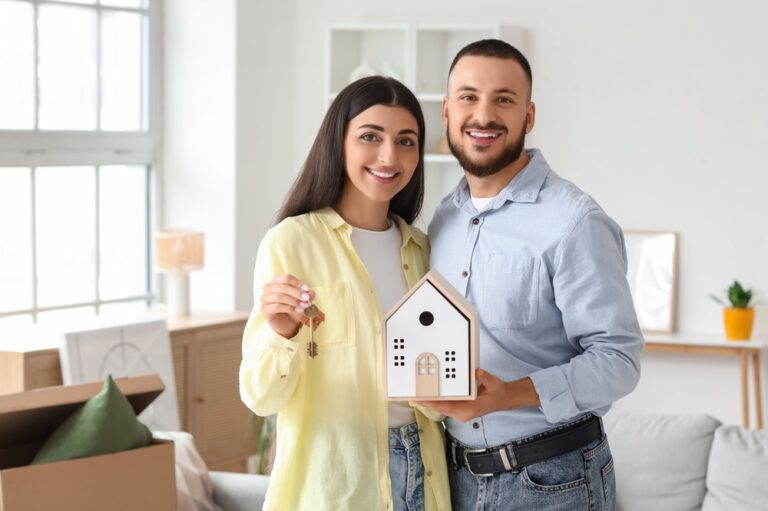 Happy,Young,Couple,With,House,Figure,And,Key,To,Rented