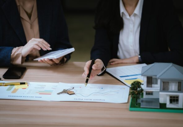 Business,Professionals,Discussing,A,House,Model,With,Documents,And,Calculator