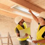 Two,Male,Construction,Workers,Using,Laptop,Inspecting,Wooden,Beams,In