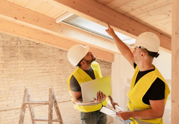 Two,Male,Construction,Workers,Using,Laptop,Inspecting,Wooden,Beams,In