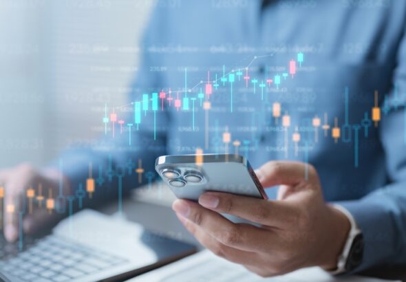 A,Person,Analyzing,Investment,Data,On,A,Smartphone,And,Laptop