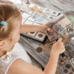 Child,With,Different,Coins,And,Banknotes,,Soft,Focus,Background
