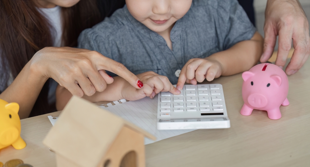 Child,Learning,About,Finances,With,Parents,Using,A,Calculator,And